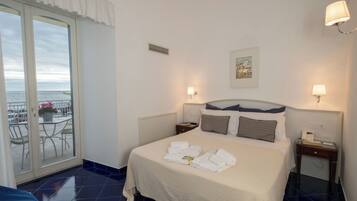 Una camera d'albergo con un letto, due comodini, una finestra vista e una porta che dà su un balcone.