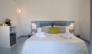 A hotel room with a bed, bedside lamps, a desk with a phone, and a small table with a vase of flowers. - Core Amalfitano City Suites (Amalfi)