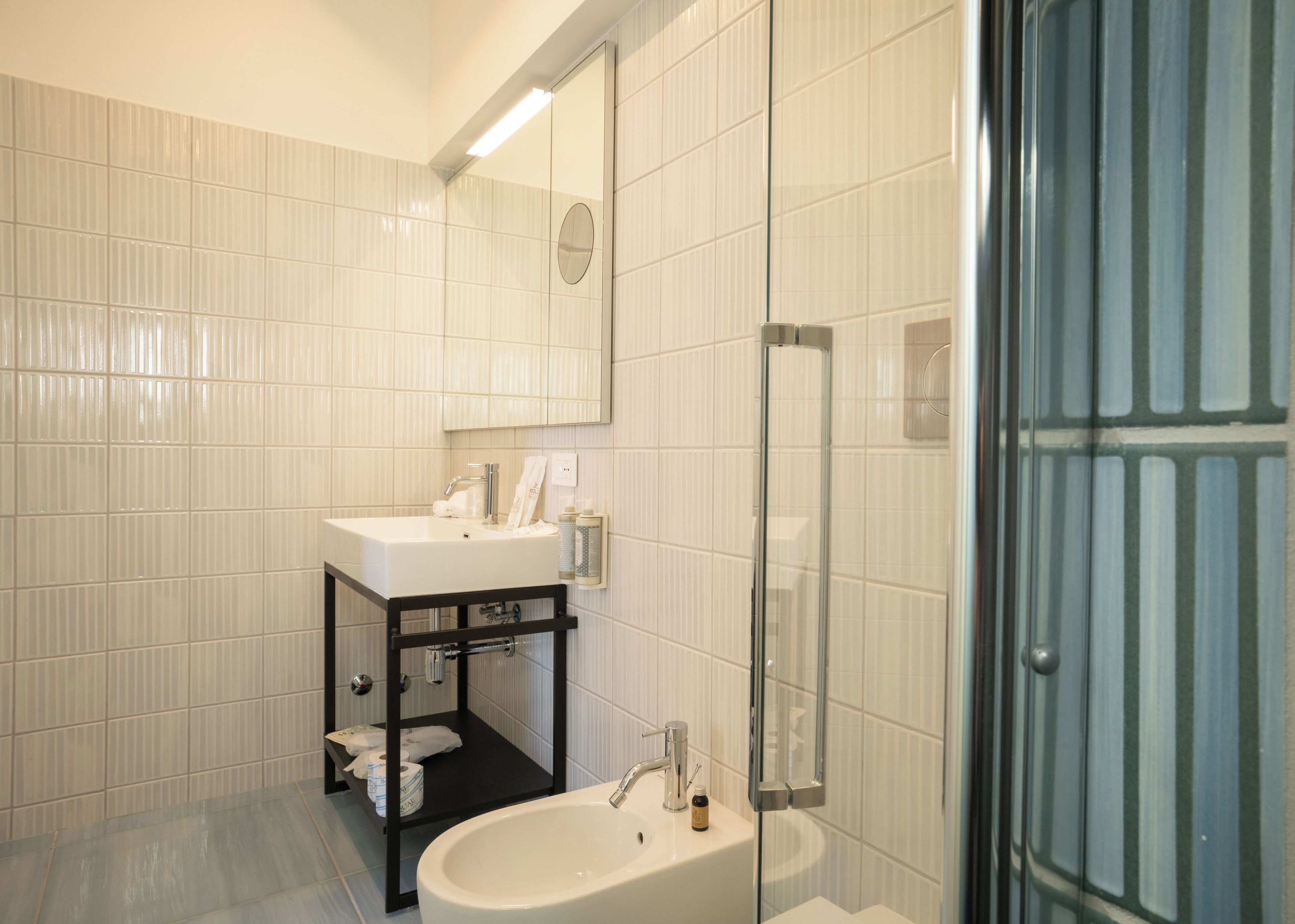Un bagno con lavandino bianco, specchio e cabina doccia in vetro.