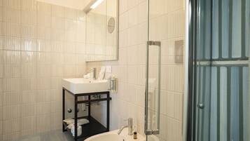 Un bagno con lavandino bianco, specchio e cabina doccia in vetro.