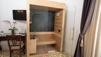 Un baño moderno con ducha de vidrio, suelo de madera y un escritorio con silla.