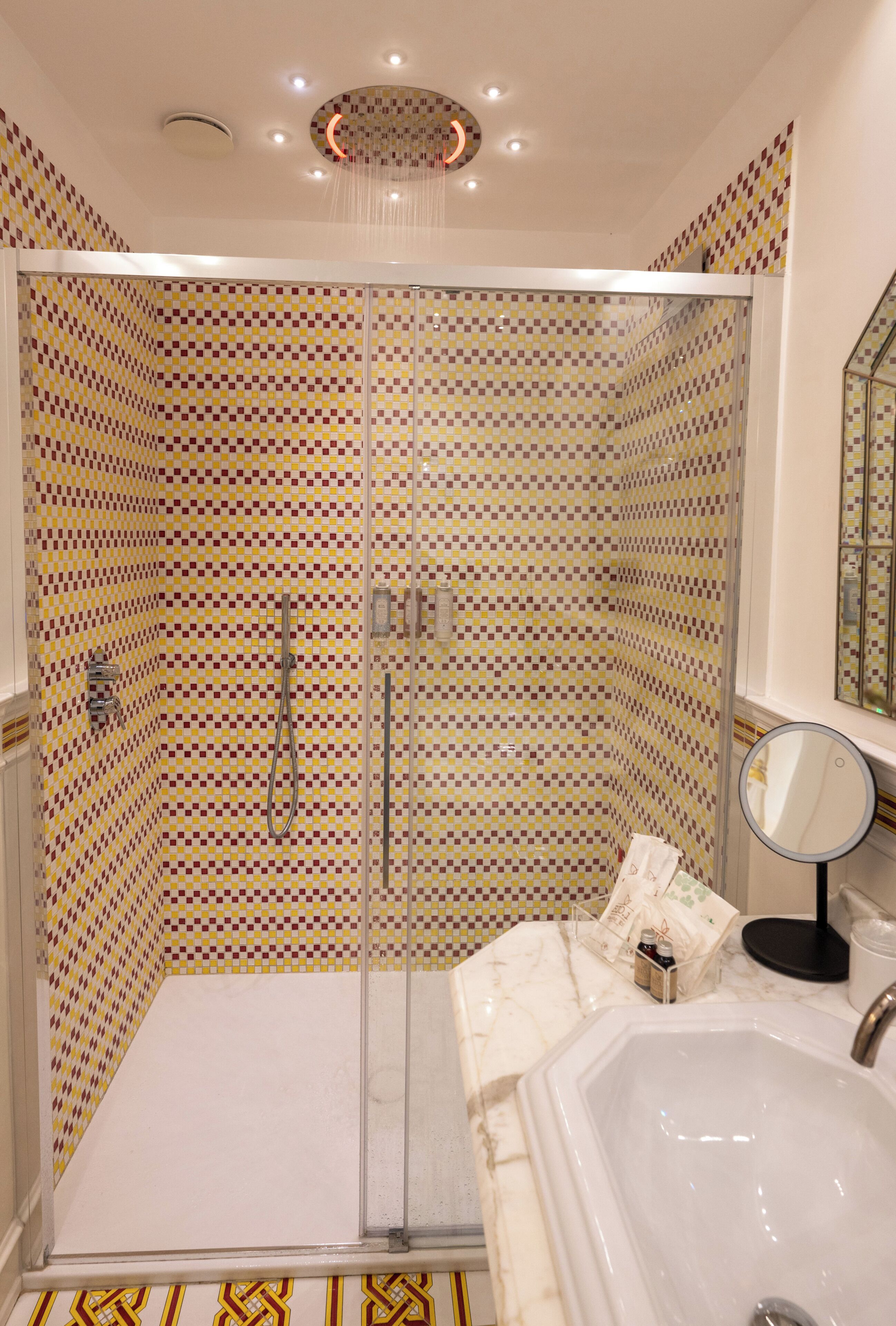 A bathroom with a shower enclosure, a sink, a mirror, and a bathtub.