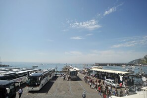 A ferry terminal with multiple buses and a docked boat. - Core Amalfitano City Suites (Amalfi)