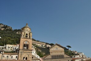 A historic building with a prominent bell tower and a facade with intricate patterns. - Core Amalfitano City Suites (Amalfi)