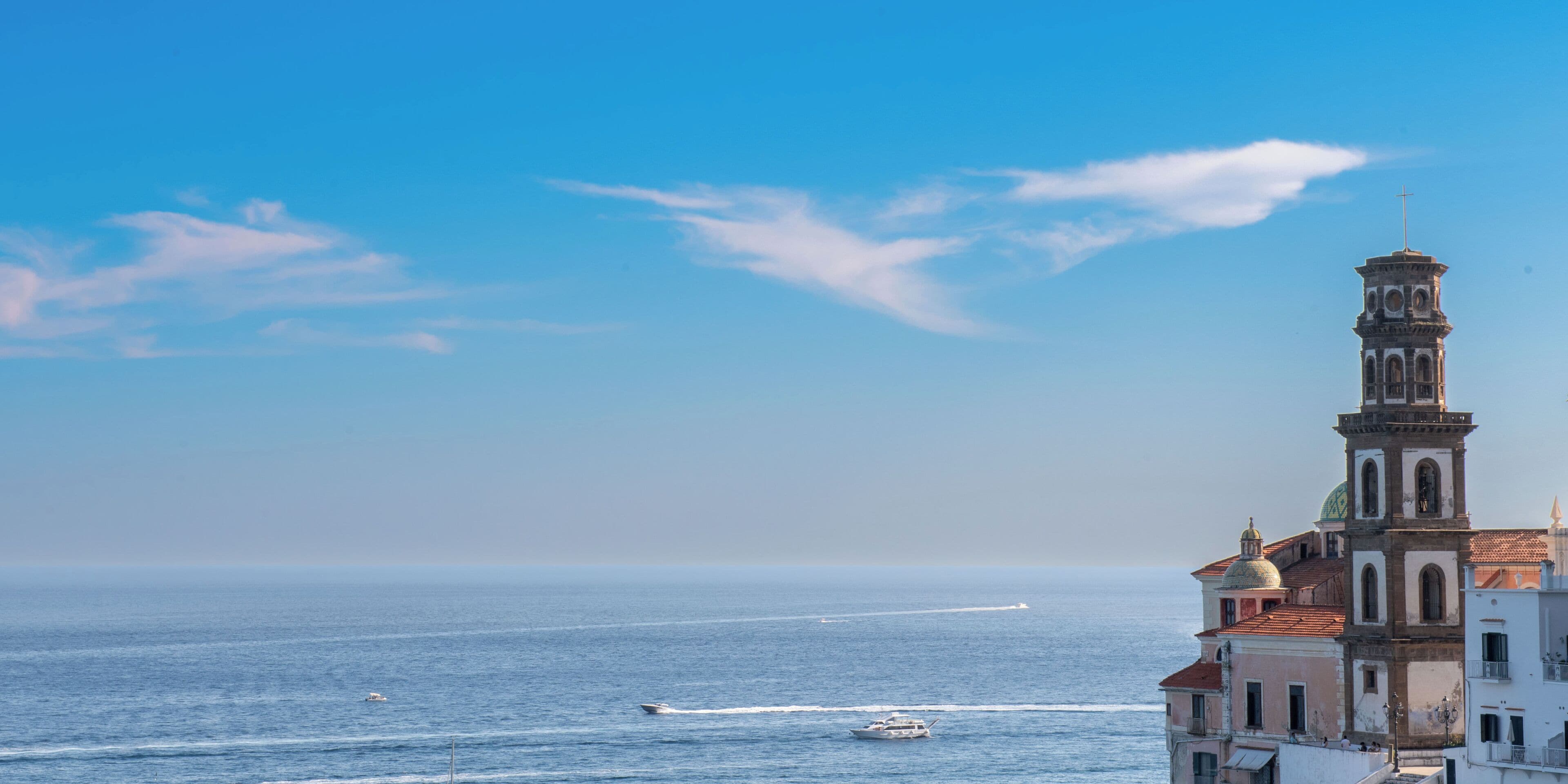 A coastal cityscape with a prominent tower and buildings along the waterfront.
