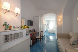 Habitación de hotel con kitchenette, zona de comedor, sala de estar con sofá y baño con ducha e inodoro.