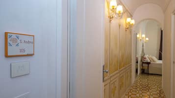 Un corridoio con una targa che indica la stanza numero 105, un interruttore della luce e una porta che conduce a una stanza con un letto e un tavolo.