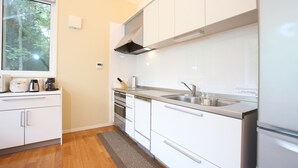 Una cocina moderna con armarios blancos, electrodomésticos de acero inoxidable, una ventana y suelo de madera.