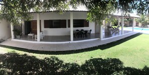 A covered patio area with a pool, outdoor seating, and a small garden.
