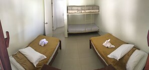 A room with two single beds, a bunk bed, and a door leading to another room.