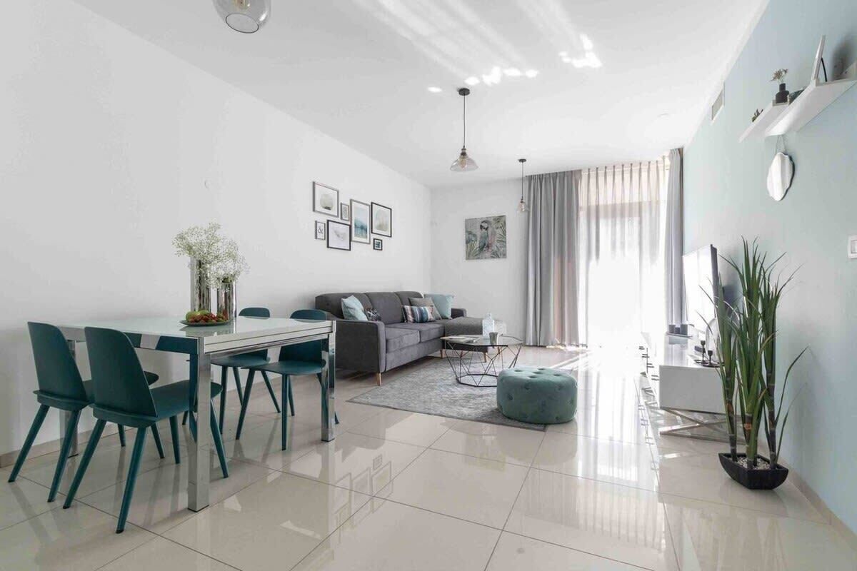 A modern living room with a sofa, coffee table, and dining area with chairs.