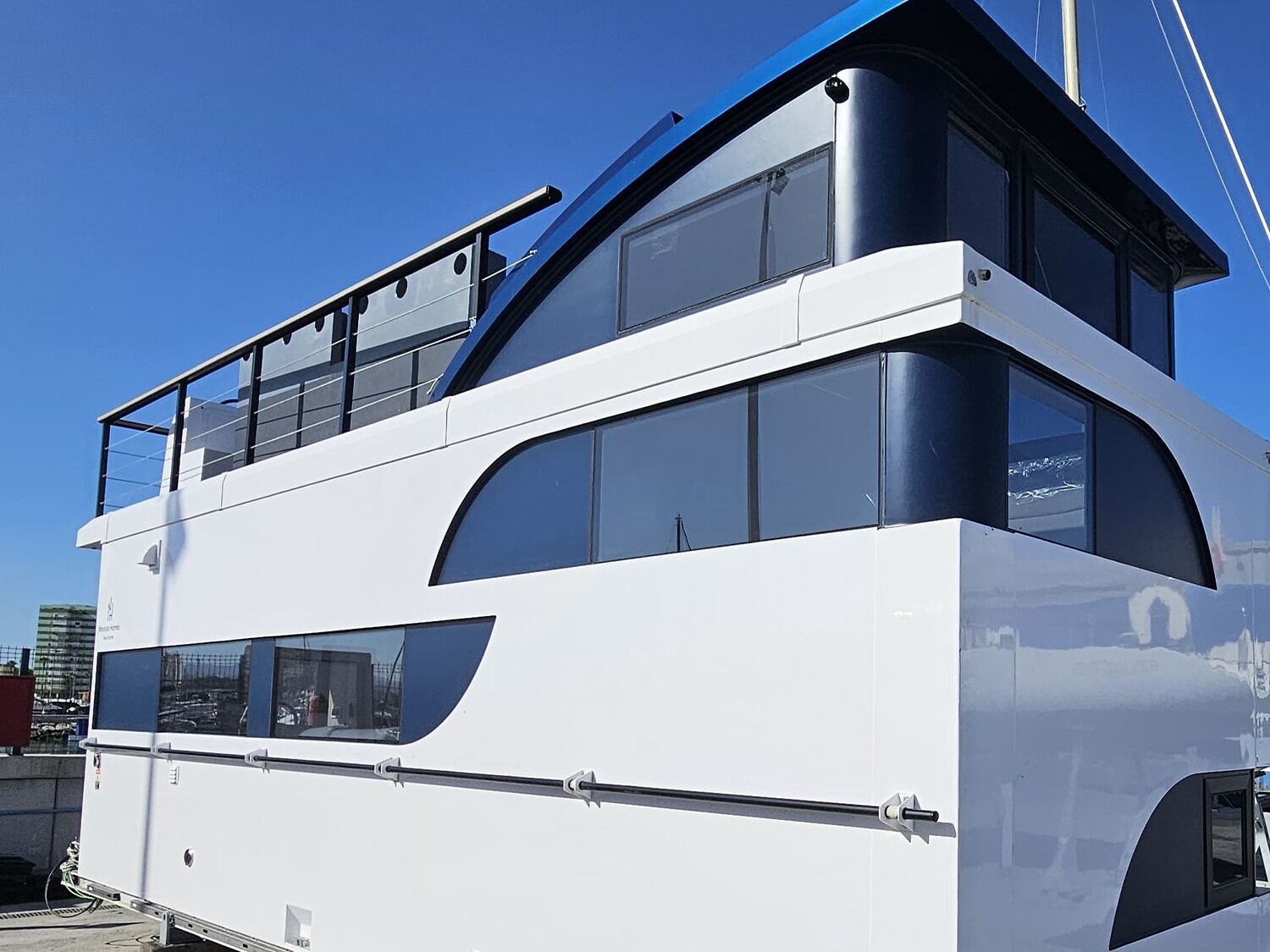 Un bateau blanc à deux ponts, doté d’un design moderne, de grandes fenêtres et d’un pont supérieur bleu.