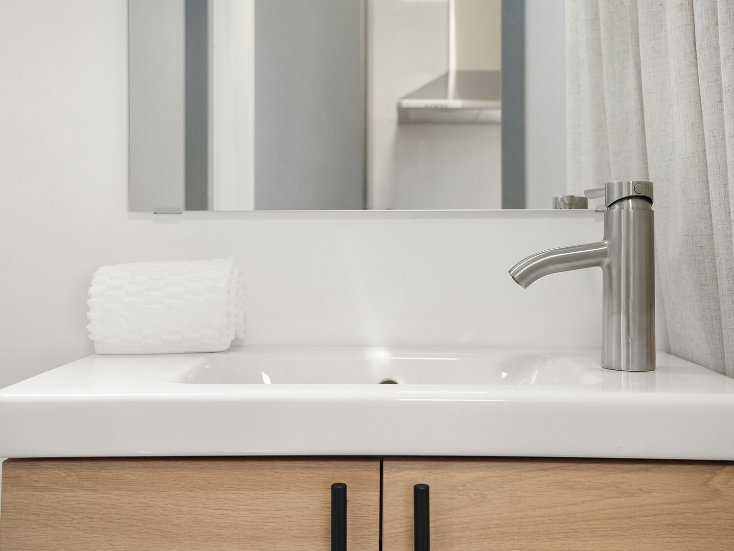 Une salle de bain moderne avec un lavabo blanc, un robinet en acier inoxydable et un miroir au-dessus.