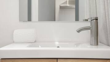 Un baño moderno con un lavamanos blanco, un grifo de acero inoxidable y un espejo encima.