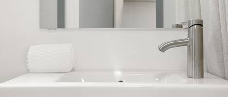 Une salle de bain moderne avec un lavabo blanc, un robinet en acier inoxydable et un miroir au-dessus.