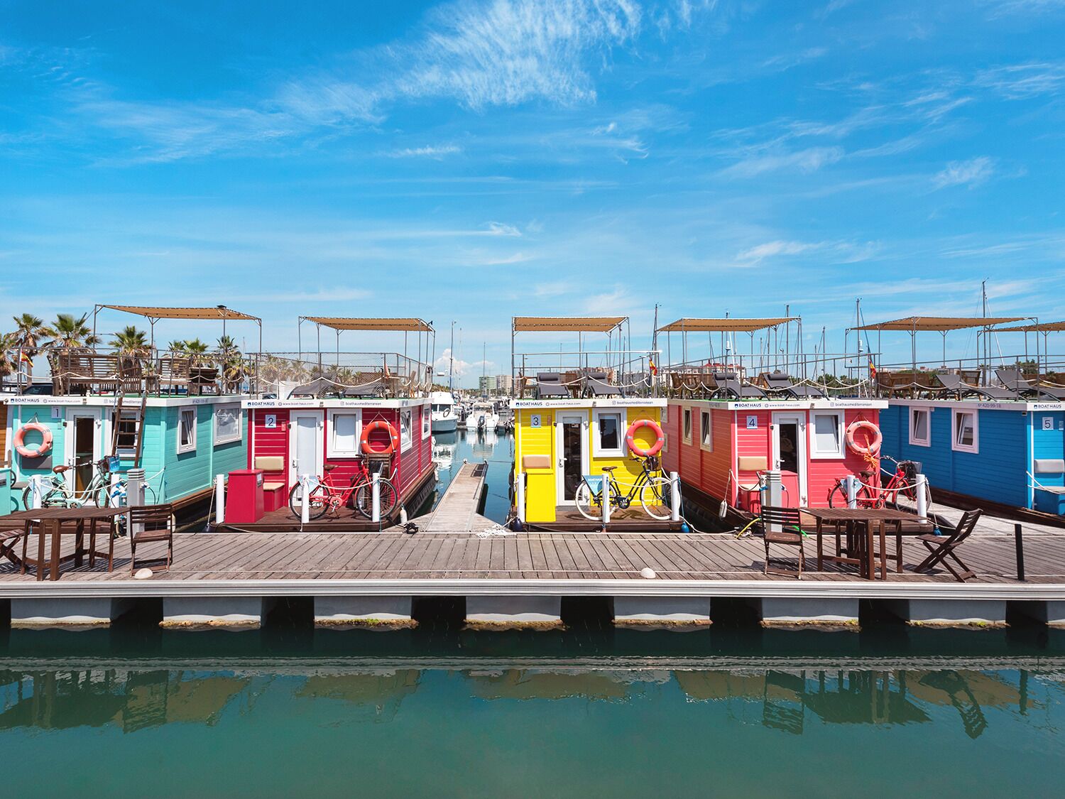 Una hilera de casas flotantes de colores con terrazas de madera y bicicletas.