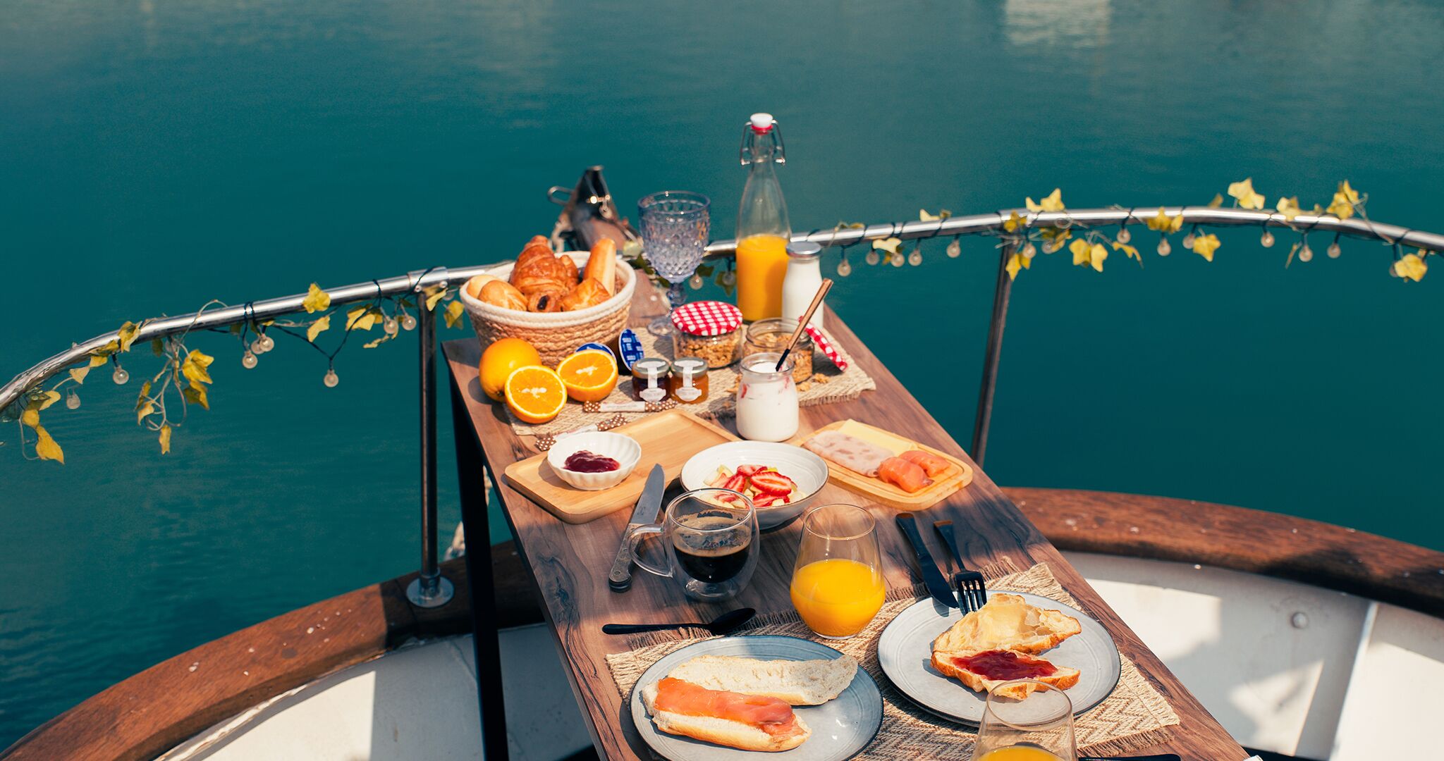 Un bateau avec une table dressée pour le petit-déjeuner, comprenant du pain, des œufs et des fruits.