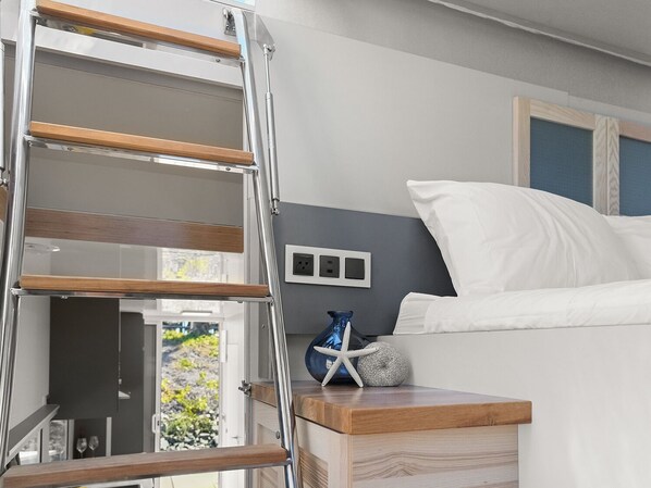 A bedroom with a wooden ladder, a bedside table with a vase, and a bed with white bedding. - Boat Haus Mediterranean Experience Alcaidesa La Linea (La Línea de la Concepción)