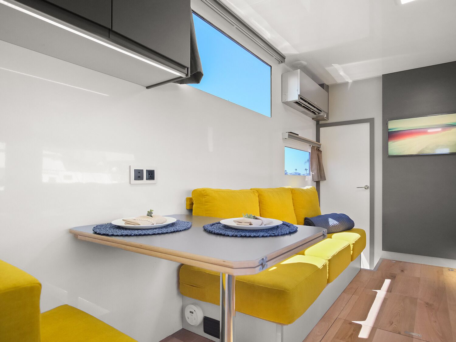 Une cuisine de taille réduite avec une table à manger, un canapé jaune et une petite fenêtre.