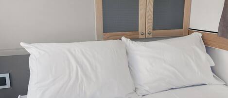 A bed with white bedding and a wooden headboard with two glass panels.