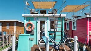 A colorful boat house with a wooden deck, a lifebuoy, bicycles, and a sign for Boat Haus. - Boat Haus Mediterranean Experience Alcaidesa  La Linea (La Línea de la Concepción)
