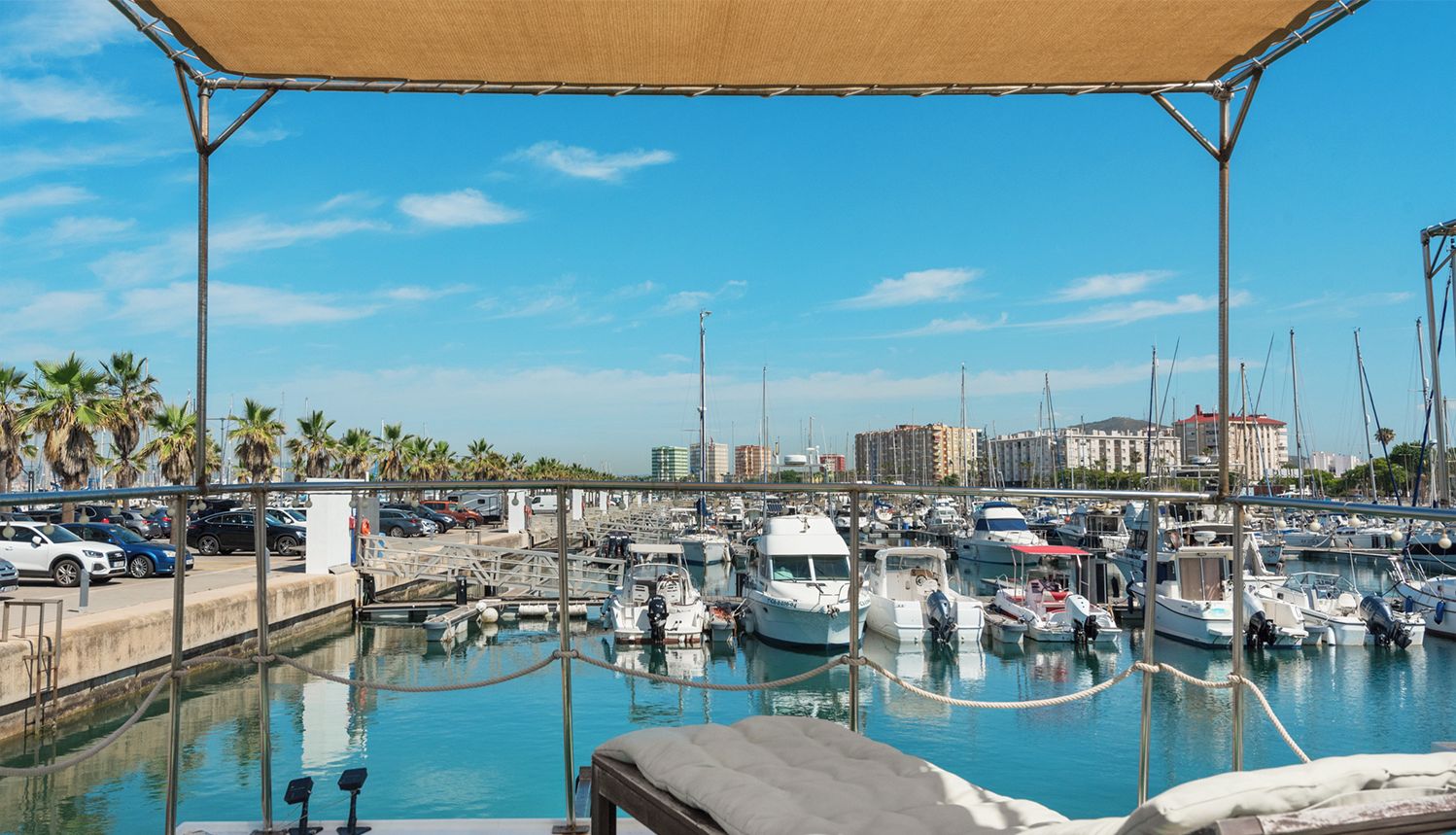 Un port de plaisance avec des bateaux amarrés, un espace piscine avec des chaises longues et une vue sur les gratte-ciel de la ville.