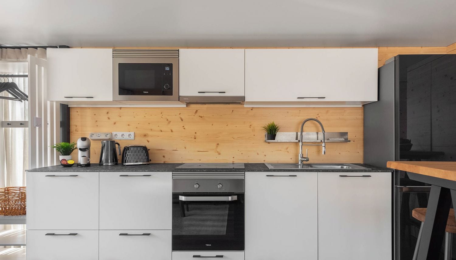 Una cocina moderna con armarios blancos, microondas integrado y estufa.