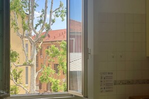 A room with a window overlooking a building with red tiles and a tree in front. - BNBOOK-BORROMEO 2 RHO (RHO)