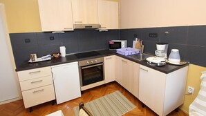 A compact kitchen with a microwave, oven, and coffee maker. - ROKOV Two-Bedroom Apartment (Rovinj)