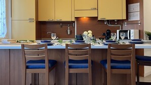 A modern kitchen with wooden cabinets, a central island with bar stools, and pendant lighting.