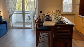 A dining area with a table set for four, a blue sofa, and a view through a glass door to an outdoor area.