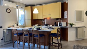 A modern kitchen with a central island, wooden chairs, and pendant lighting.