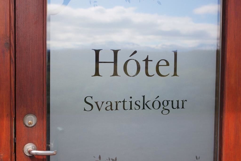 A hotel sign with the name "Hôtel Svartiskögur" on a glass door.