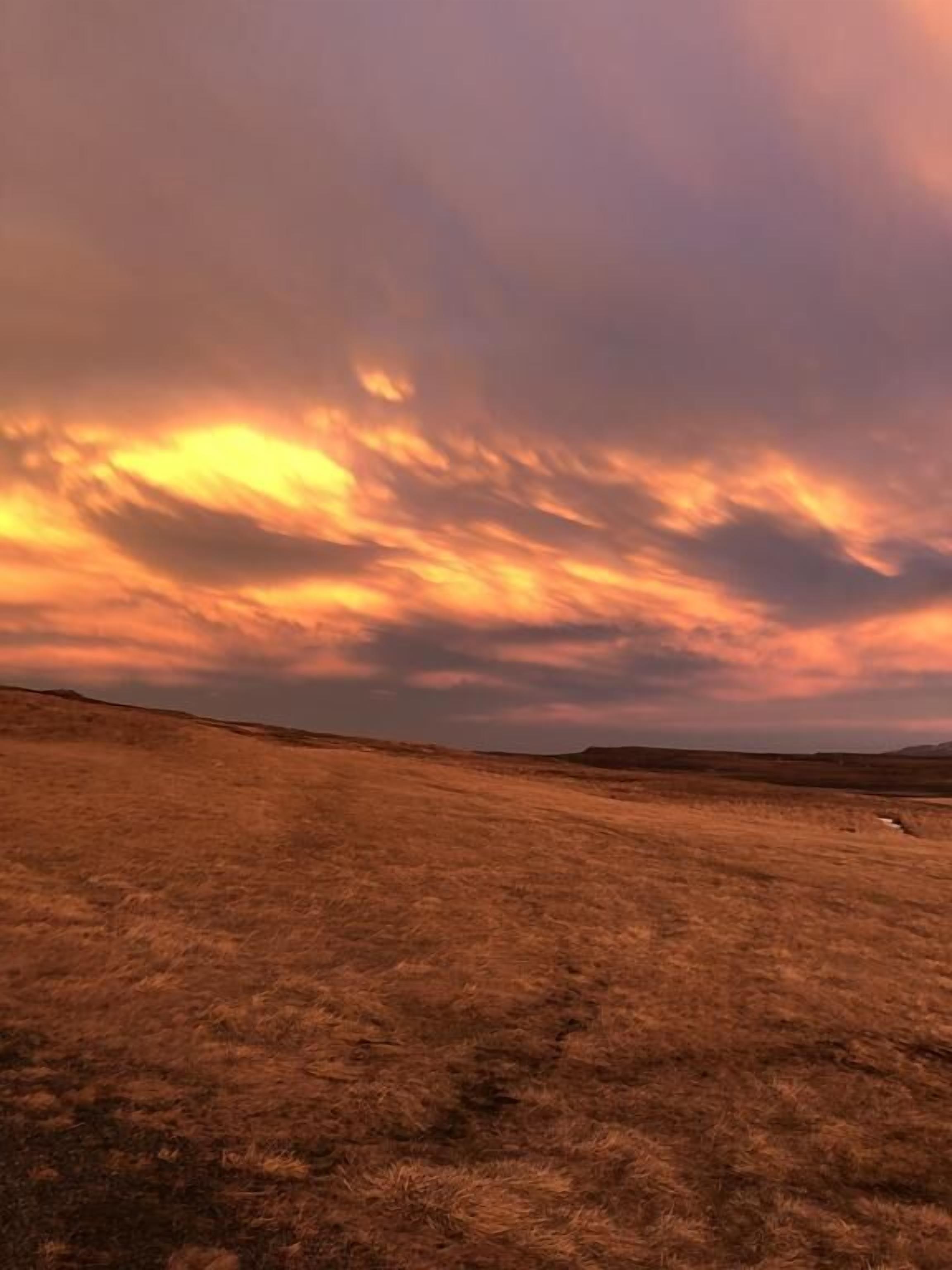 Un extenso campo abierto con un cielo de atardecer espectacular.