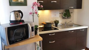 A modern kitchen with a microwave, kettle, and a small potted plant. - Bnbook Passirana Studio with fast wifi (RHO)