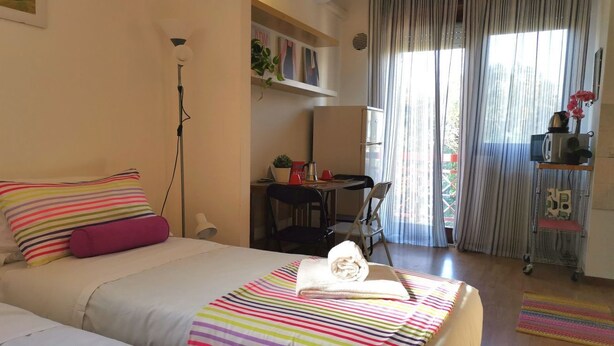 A hotel room with a bed, a desk, a chair, and a small table with a plant. - Bnbook Passirana Studio with fast wifi (RHO)