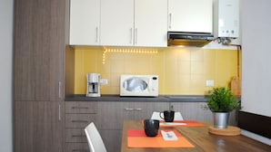 Une cuisine moderne avec des meubles blancs, un four à micro-ondes et une machine à café.
