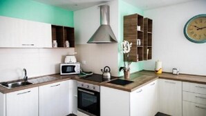 A compact kitchen with white cabinets, a stainless steel range hood, a microwave, an oven, and a sink. - Bnbook Don Sturzo with super wi fi (Cornaredo)