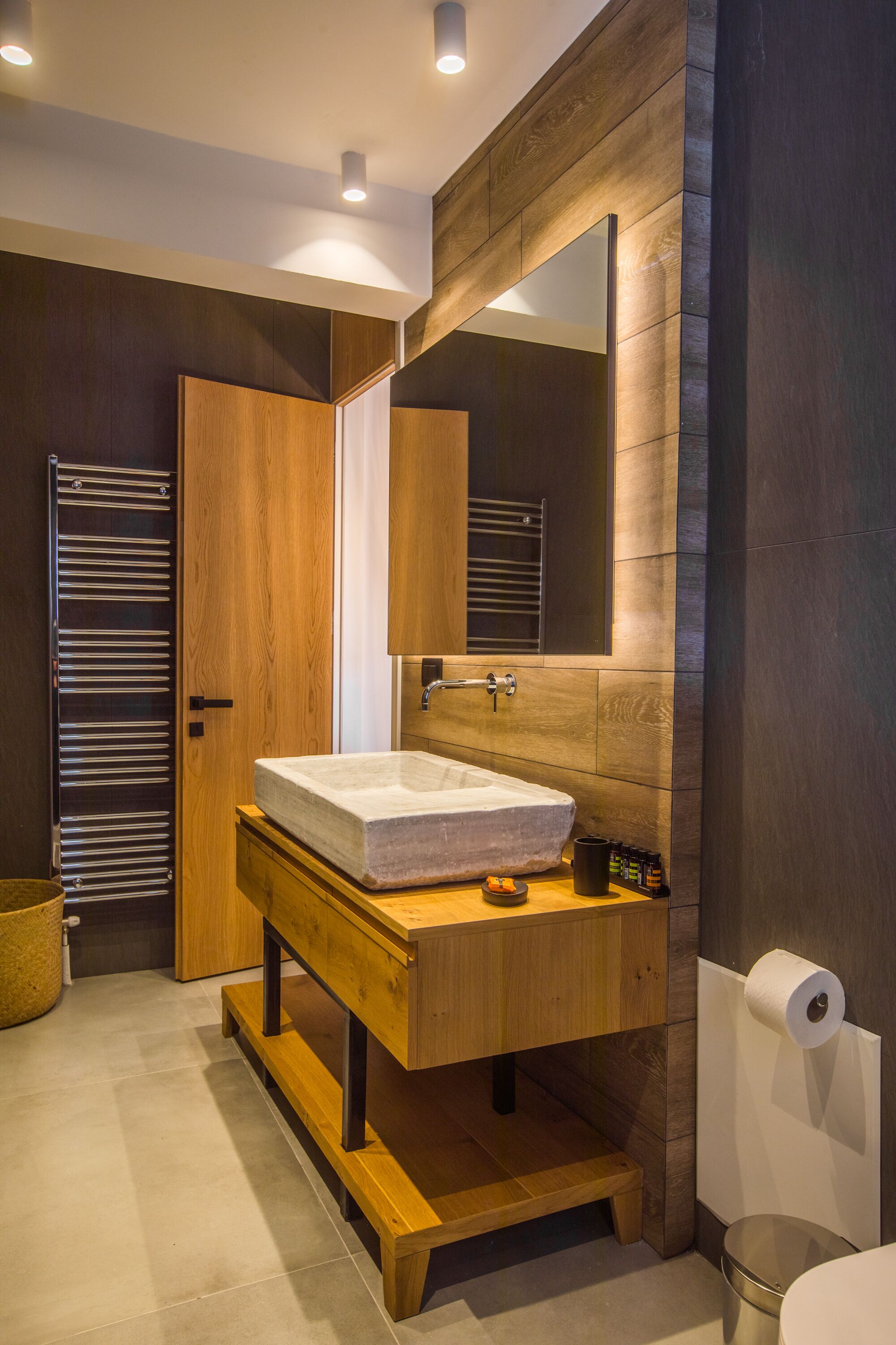 A modern bathroom with a wooden vanity, a large mirror, and a built-in sink.