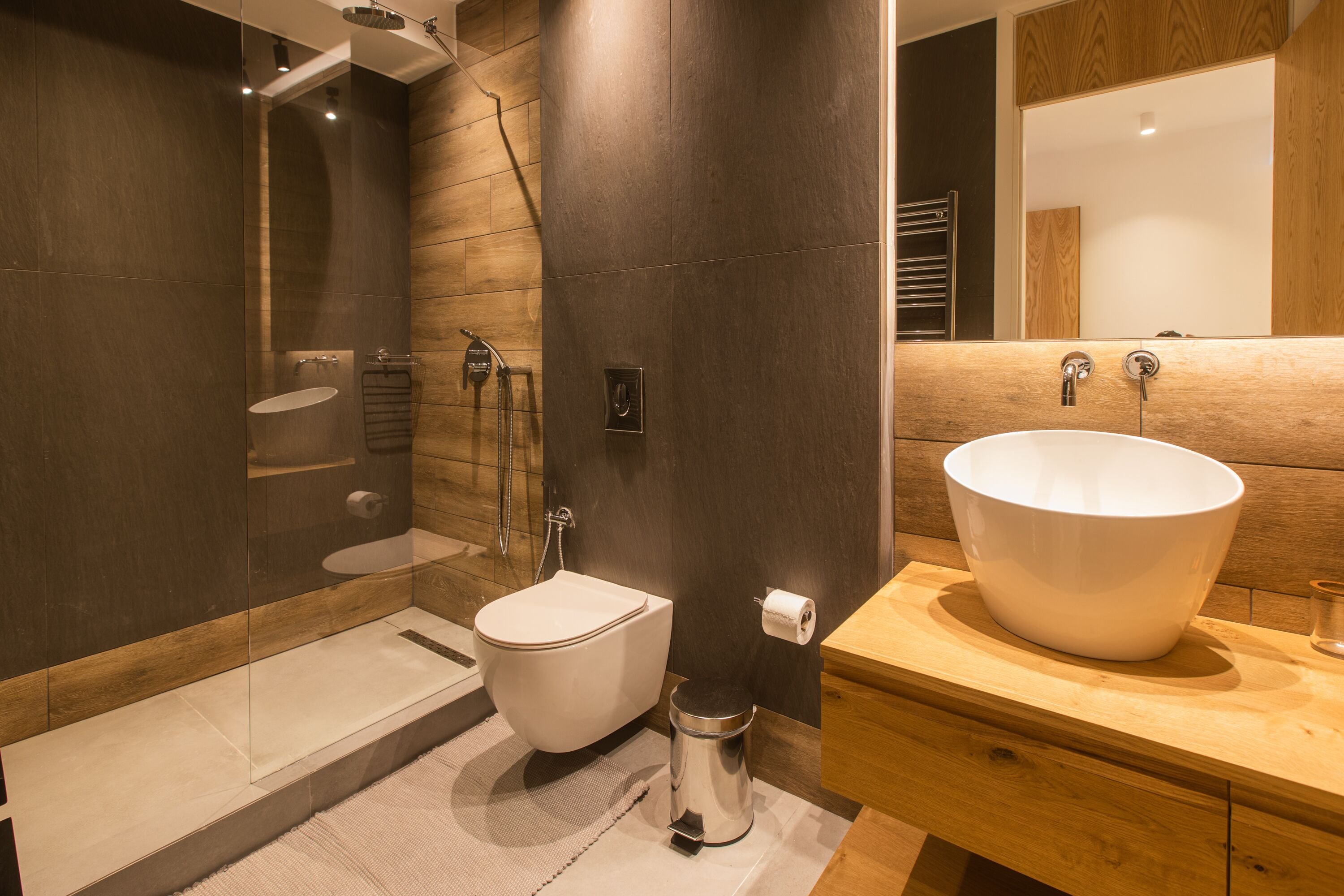 A modern bathroom with a large white sink, a toilet, and a shower area.
