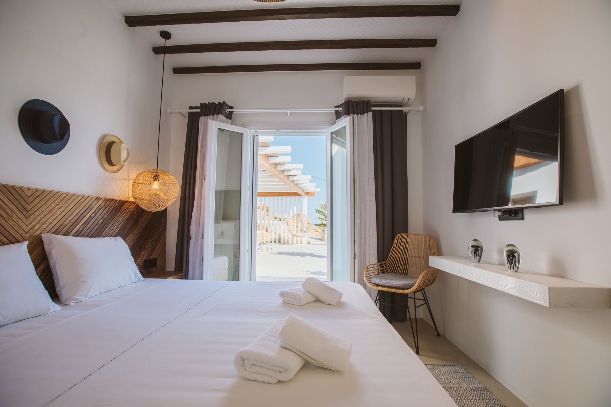 Ein Hotelzimmer mit Bett, Handtüchern, Fernseher, Sessel und Blick nach draußen.