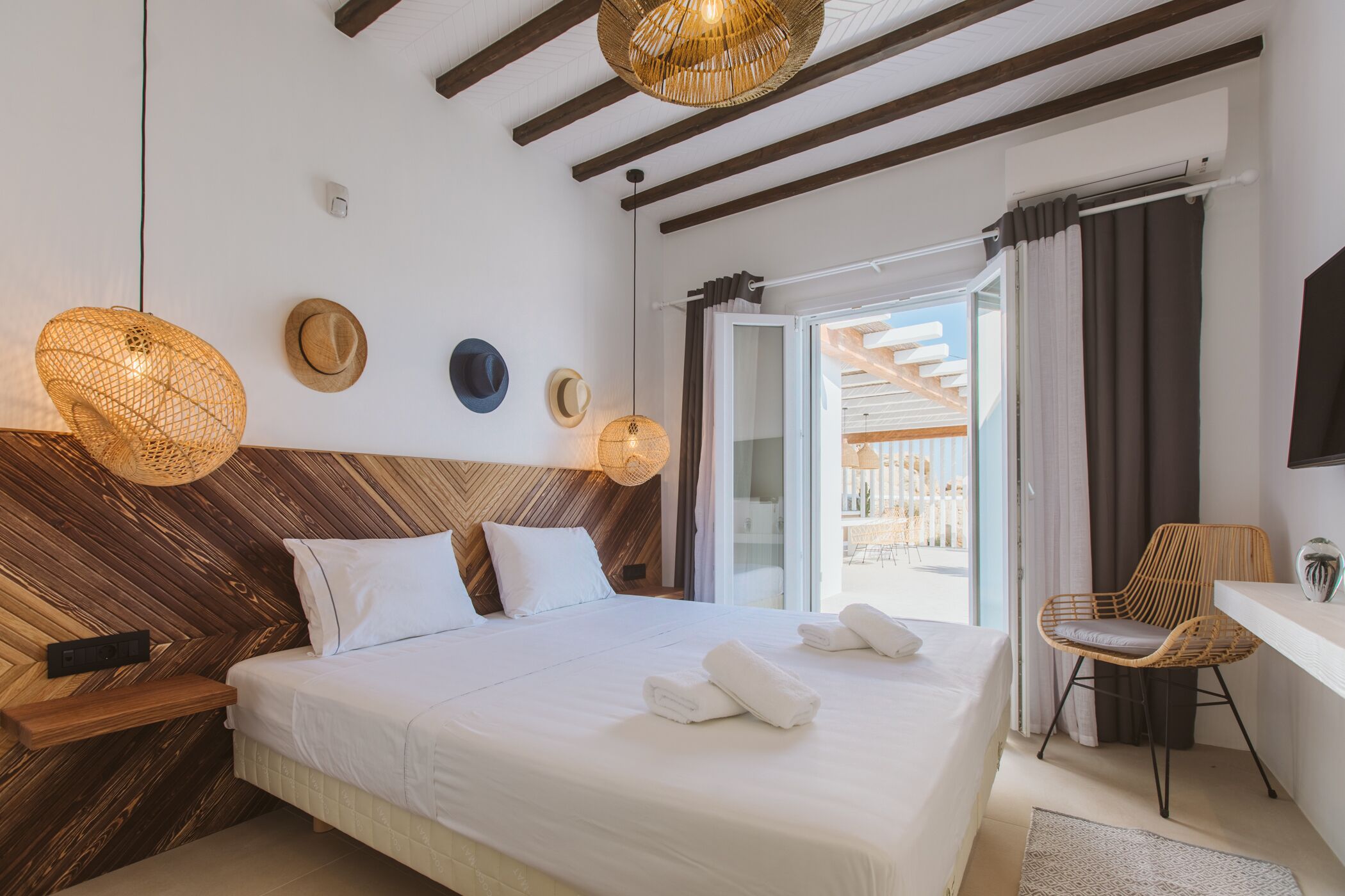 A bedroom with a large bed, wooden headboard, and a wicker light fixture.