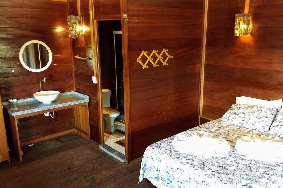 A wooden room with a bed, a sink, and a toilet.