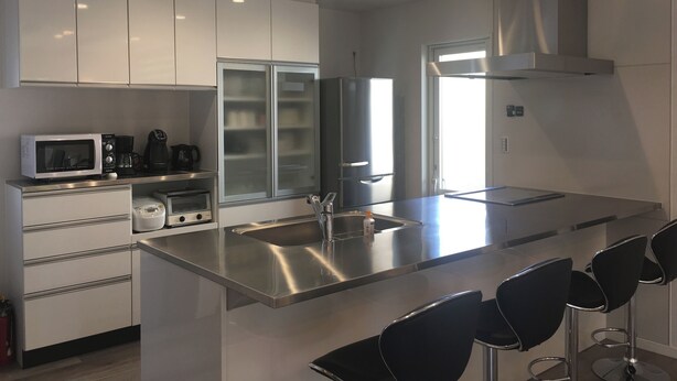 Una cocina moderna con electrodomésticos de acero inoxidable, horno empotrado y una isla grande con pileta y taburetes de bar.