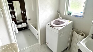 Une petite buanderie équipée d’un lave-linge, d’un étendoir et d’une fenêtre qui laisse entrer la lumière naturelle.
