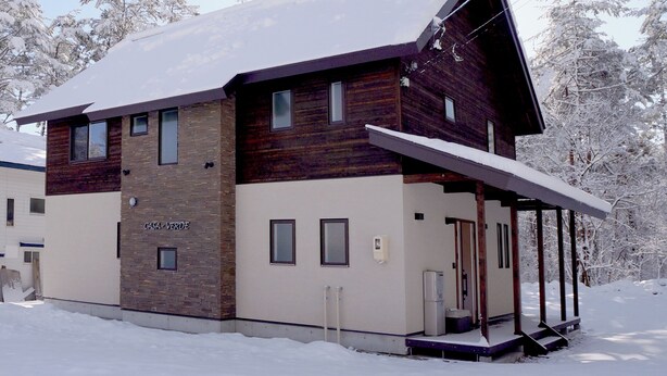 Un bâtiment moderne à deux étages, doté d'un télésiège, d'une façade en bois et d'une entrée abritée.