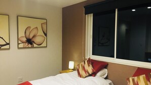 Une chambre d’hôtel avec deux lits, une fenêtre et des œuvres d’art murales.