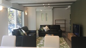 Una sala de estar moderna con dos sofás negros, una mesa de centro blanca y un televisor.