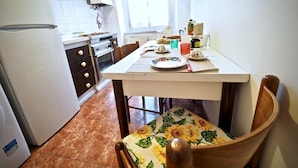 Una cocina compacta con refrigerador, horno y una mesa de comedor dispuesta con platos y tazas.