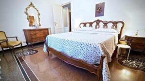 Un dormitorio con una cama de madera, un aparador, una silla y un espejo.